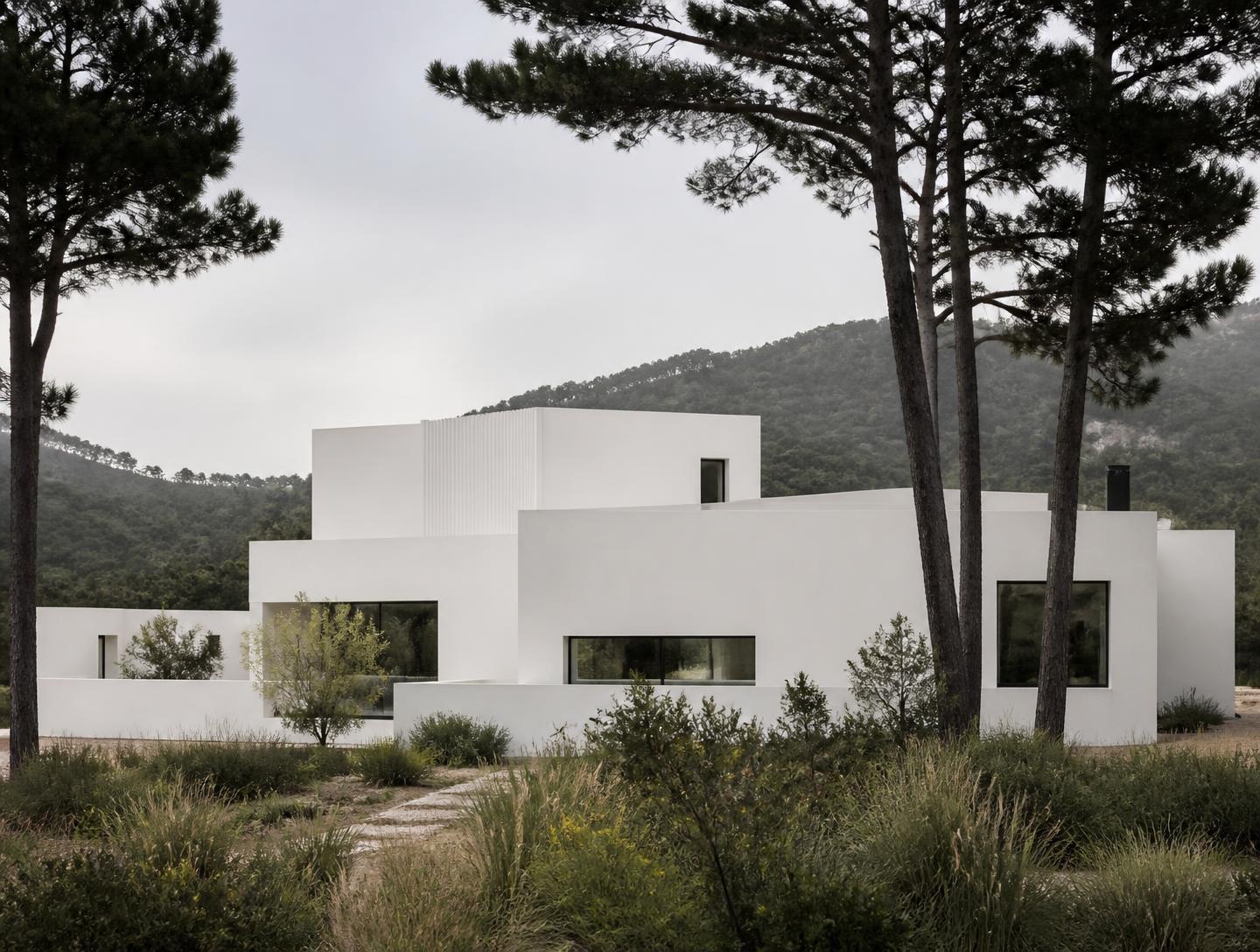 Habitação unifamiliar de volumes brancos entre pinheiros na serra de Sintra