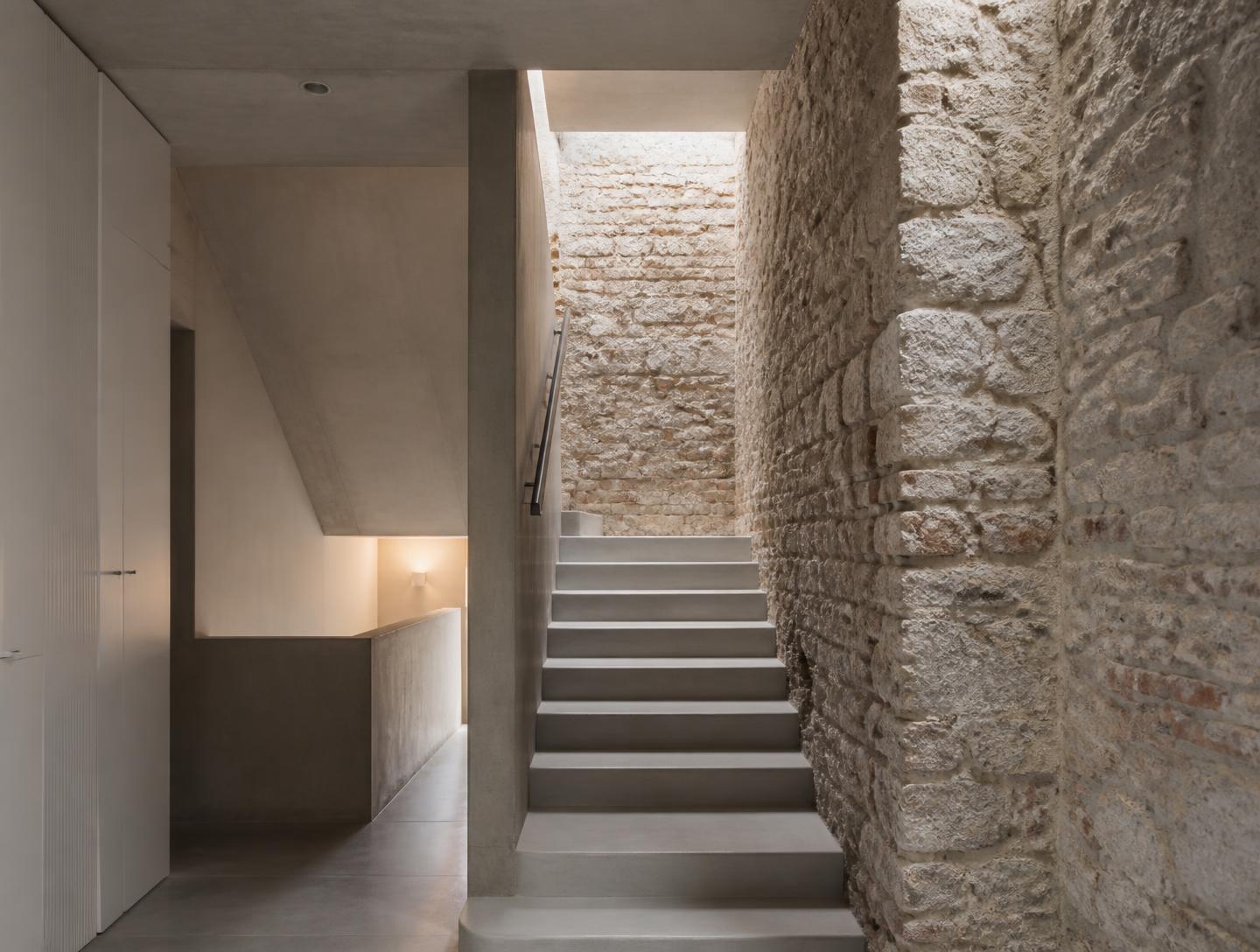 Escada de betão contemporânea junto a parede de alvenaria de pedra recuperada